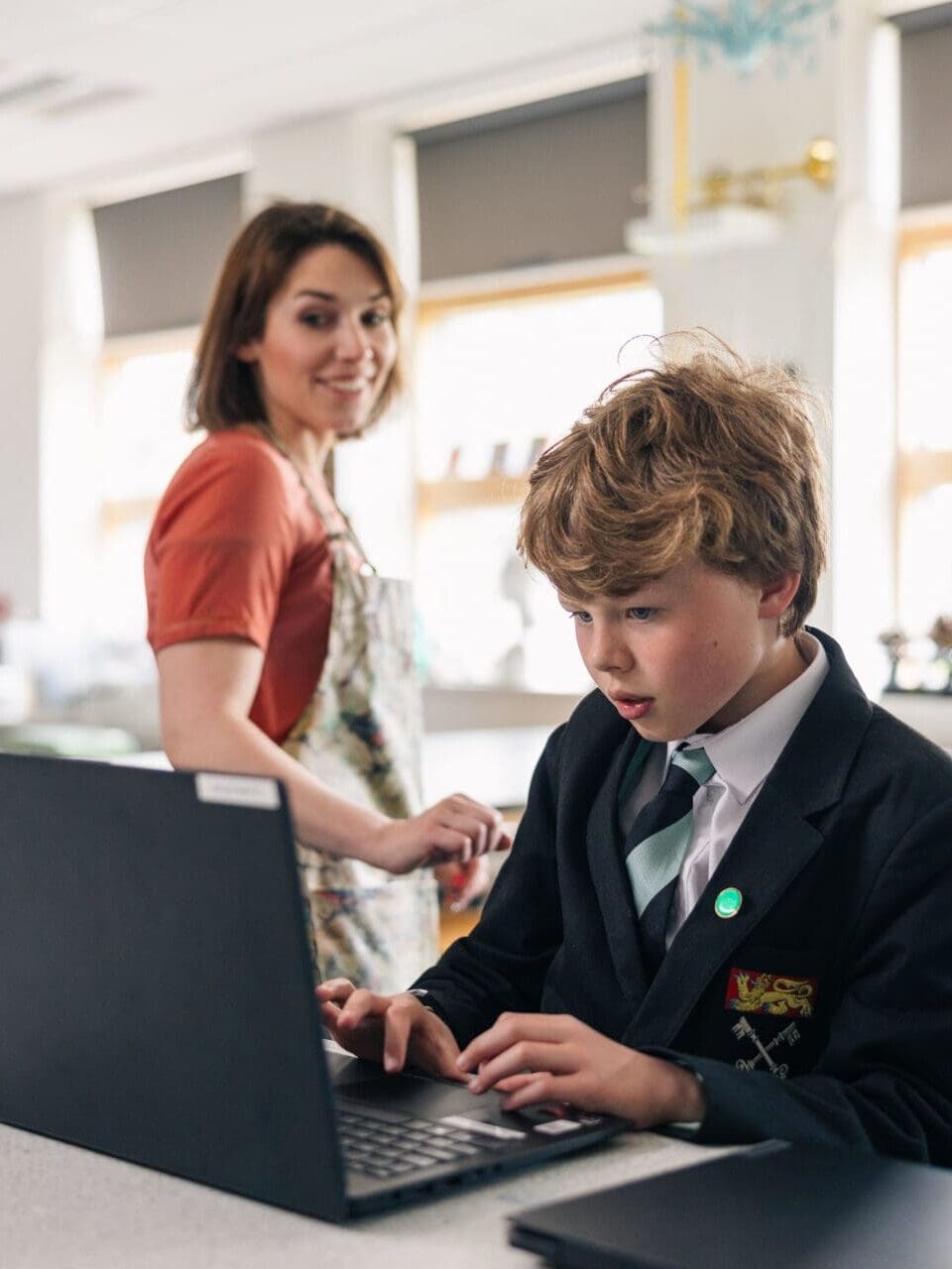 Image of a teacher looking over a pupil working on a computer